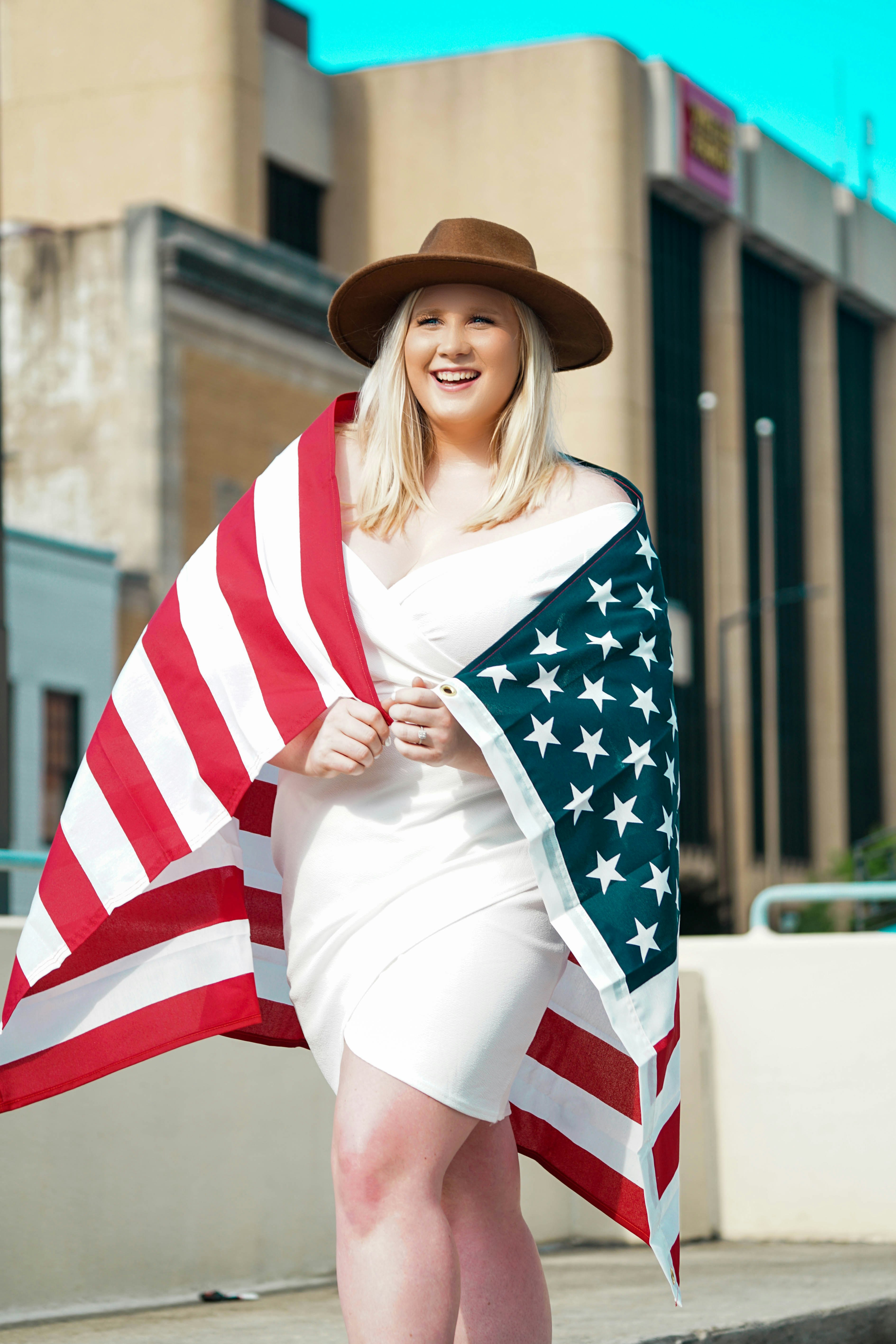 woman in white shirt and blue and white checkered scarf wearing brown hat